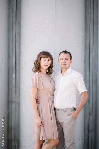 love story, beautiful couple a man and a woman in bright clothes, dress standing near a gray wall, hugging, smile, family, a date, a walk © liliyabatyrova