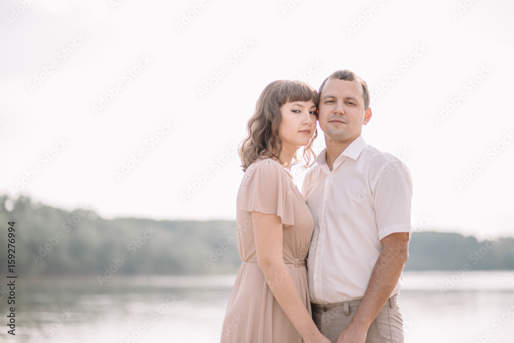 love story, beautiful couple a man and a woman in bright clothes, dress walking along the river Bank,are holding hands, summer, nature