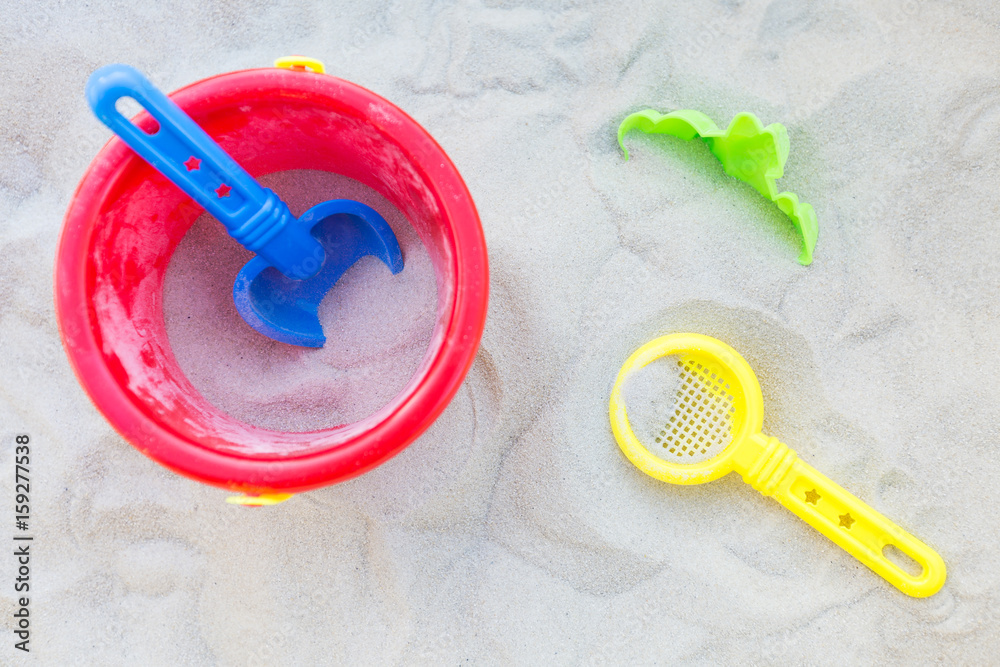 Plastic bucket, sifter and a small shovel in the sand; view from above Plastic bucket, sifter and a small shovel in the sand; view from above