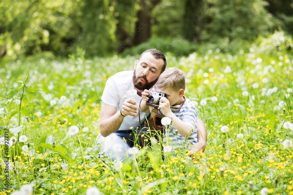 Fototapeta premium Young father with little boy with camera in summer park.