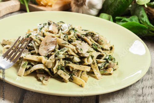 Tagliatelle pasta with spinach and mushrooms on a plate.