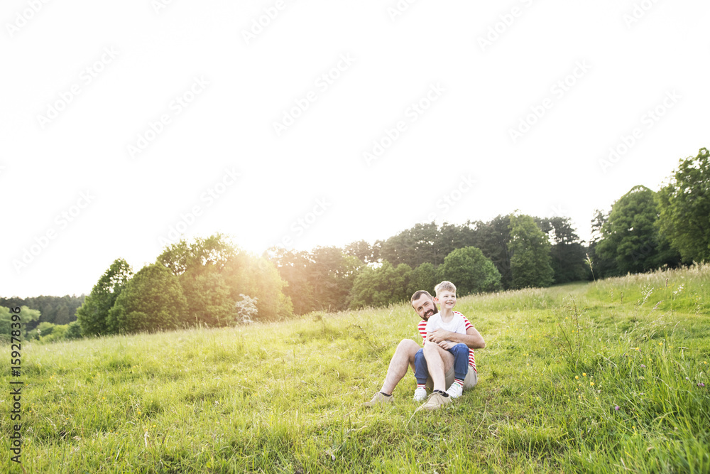 Hipster father and little son on green meadow. Sunny summer day.