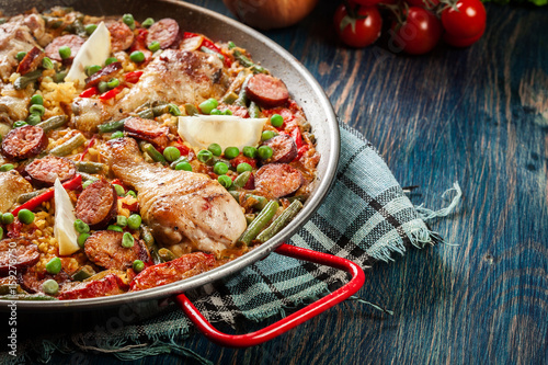 Traditional paella with chicken legs, sausage chorizo and vegetables served in paellera photo