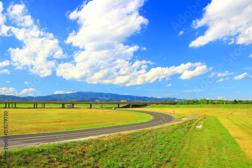 Road and overpass, clouds on blue sky in background 
