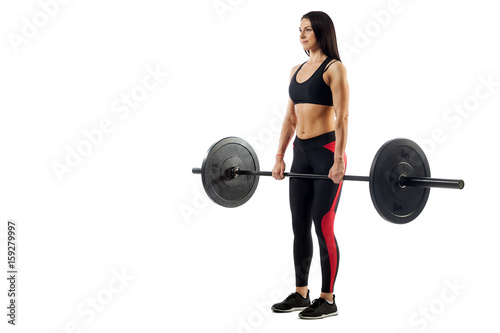Young athletic sporty woman fitness model doing deadlift with a barbell on white isolated background, standing at the top