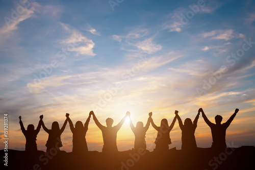 Silhouette of happy business team making high hands in sunset sky background for business teamwork concept photo