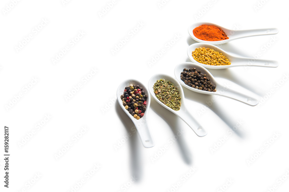 Close-up view of assorted dried aromatic spices in ceramic spoons isolated on white Close-up view of assorted dried aromatic spices in ceramic spoons isolated on white