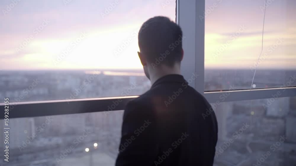Man is standing by the panoramic window close-up Man is standing by the panoramic window close-up