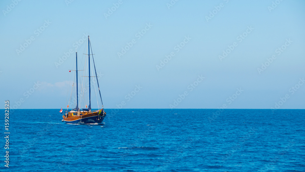 A ship with the sails down on the sea horizon.