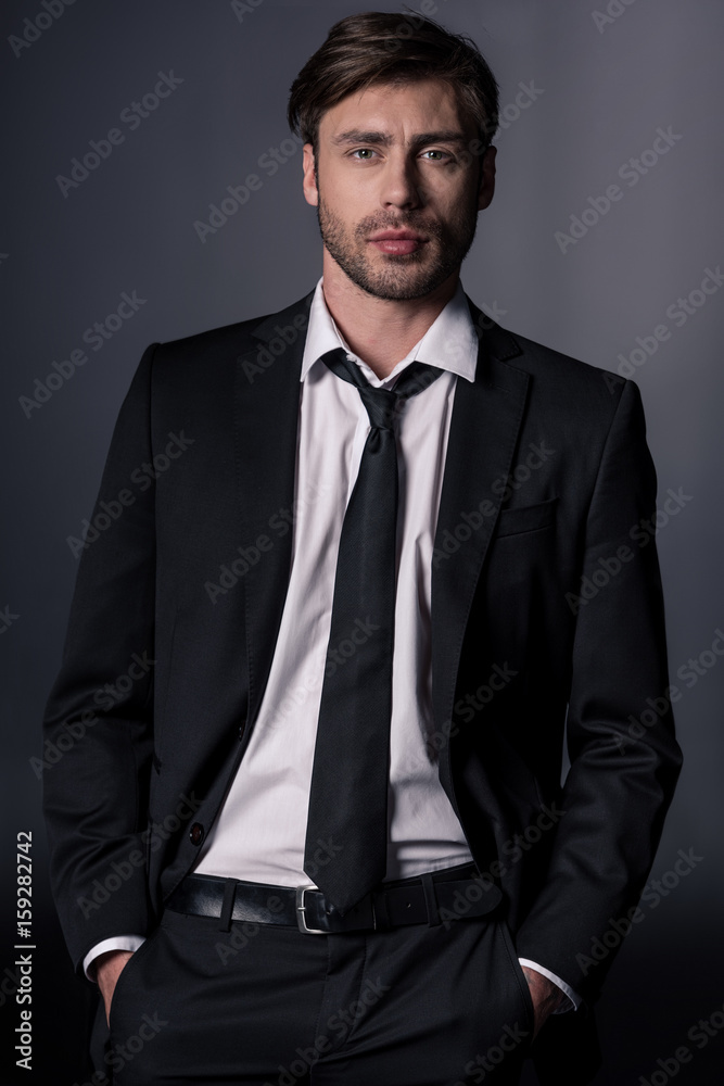 portrait of young stylish man in suit looking at camera isolated on black portrait of young stylish man in suit looking at camera isolated on black