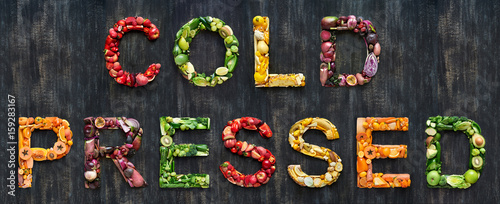 Cold pressed juice vegetables words spelled out with healthy organic fruit on rustic background