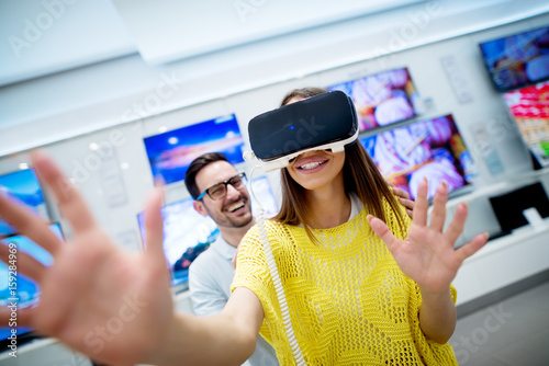 Couple in electronics store, exploring VR goggles. photo