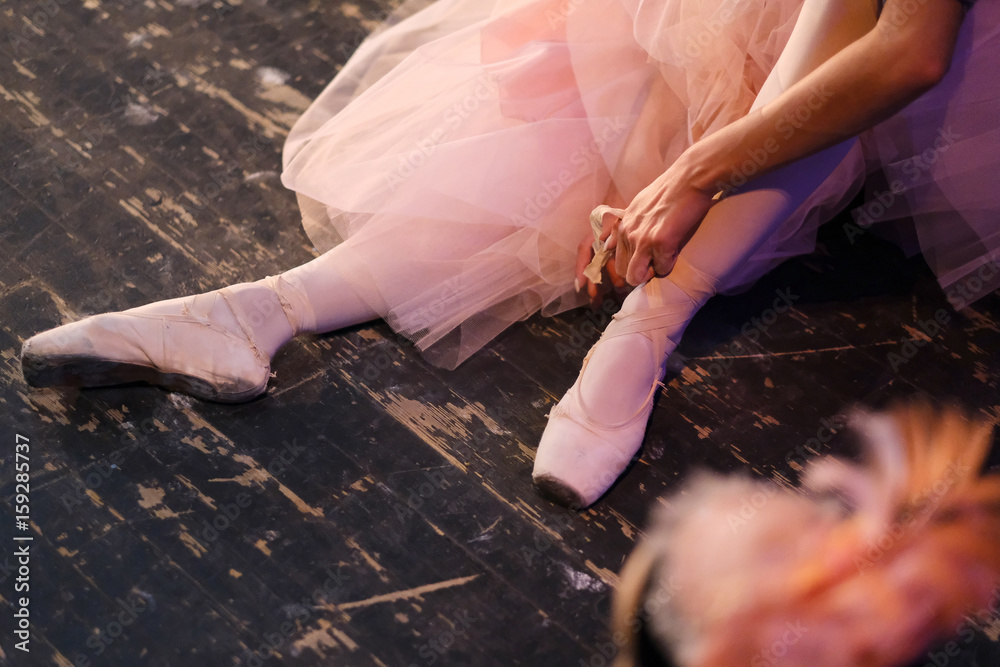 Obraz premium Ballerina is resting sitting on the floor in the rehearsal hall of the theater