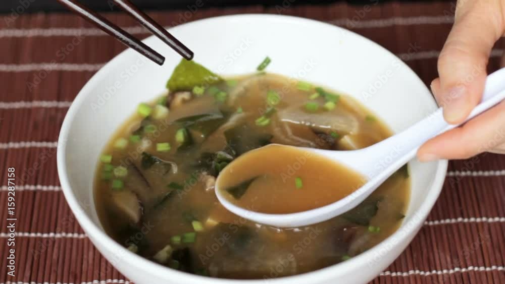 Female hands spoon out tofu and broth from miso soup and put down spoon and chopsticks. Misoshiru is traditional japanese food usually eaten with chopsticks. Female hands spoon out tofu and broth from miso soup and put down spoon and chopsticks. Misoshiru is traditional japanese food usually eaten with chopsticks.
