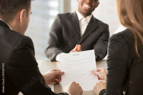 Employers or recruiters review cv of black confident job applicant smiling at background during employment interview, good resume template writing tips, hire me, starting building career, close up