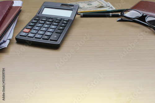 Office desk with US Dollars, smartphone with black screen, pen, calculator, wallet, and supplies with copy space