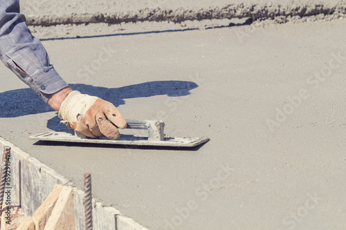 Фотография Construction worker leveling concrete pavement outdoors.