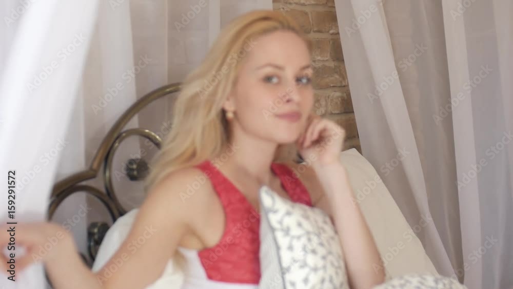 Sexy blond girl talking on mobile phone in bed. On the top hang a white canopy. Using mobile devices in everyday life. Sexy blond girl talking on mobile phone in bed. On the top hang a white canopy. Using mobile devices in everyday life.