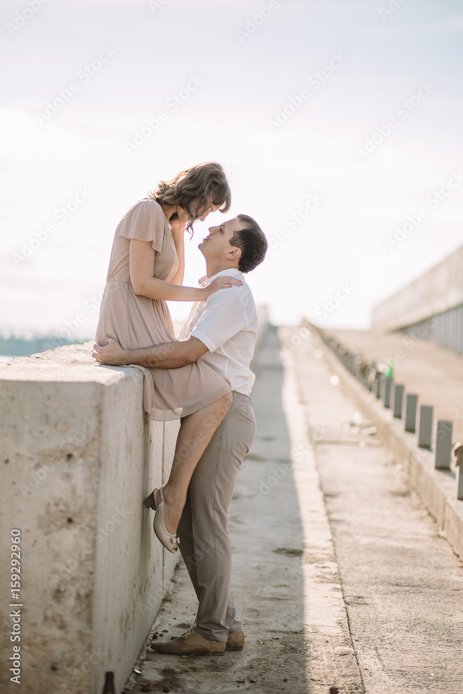 beautiful couple man and woman in a light beige light clothing spend time together, enjoy each other, talk, smile, love story on the banks of the river