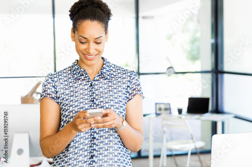 Portrait of smiling afro-american office worker with her mobile phone in offfice