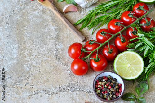 Food background with different ingredients on a marble background. Cherry tomatoes, rosemary, garlic, pepper, lime. Top view.