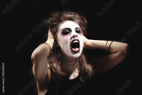 Tableau sur toile Young woman in color contact lenses, with Halloween makeup on black background