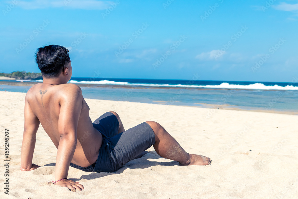 Young asian indonesian man on the beach of tropical Bali island, Indonesia. Young asian indonesian man on the beach of tropical Bali island, Indonesia.