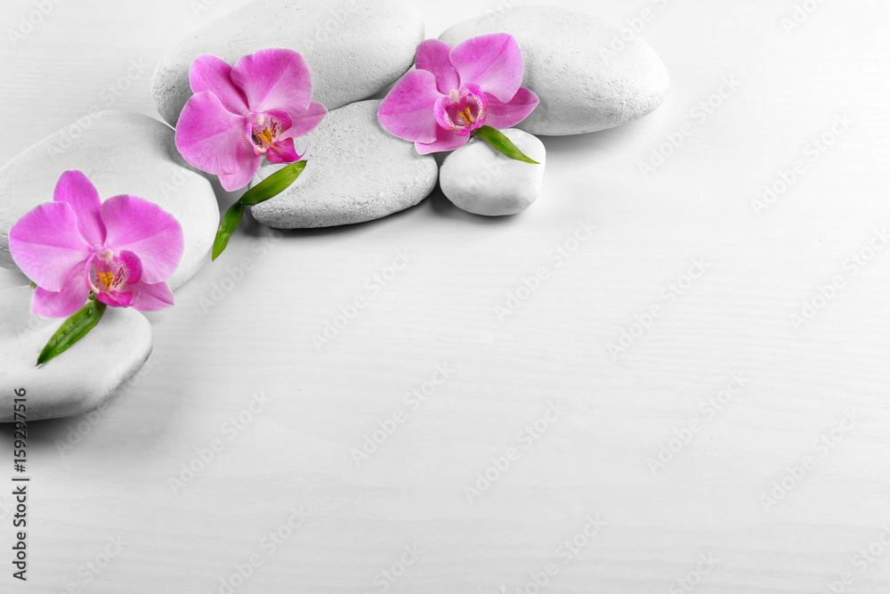 Spa stones with orchid flowers and bamboo leaves on white background