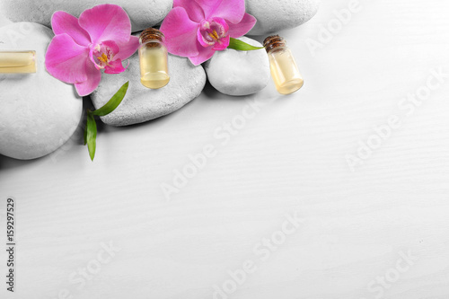 Spa stones, aroma oil with orchid flowers and bamboo leaves on white background