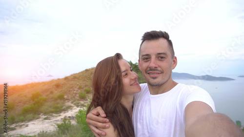 Smiling happy couple taking selfie in mountains, aerial city view