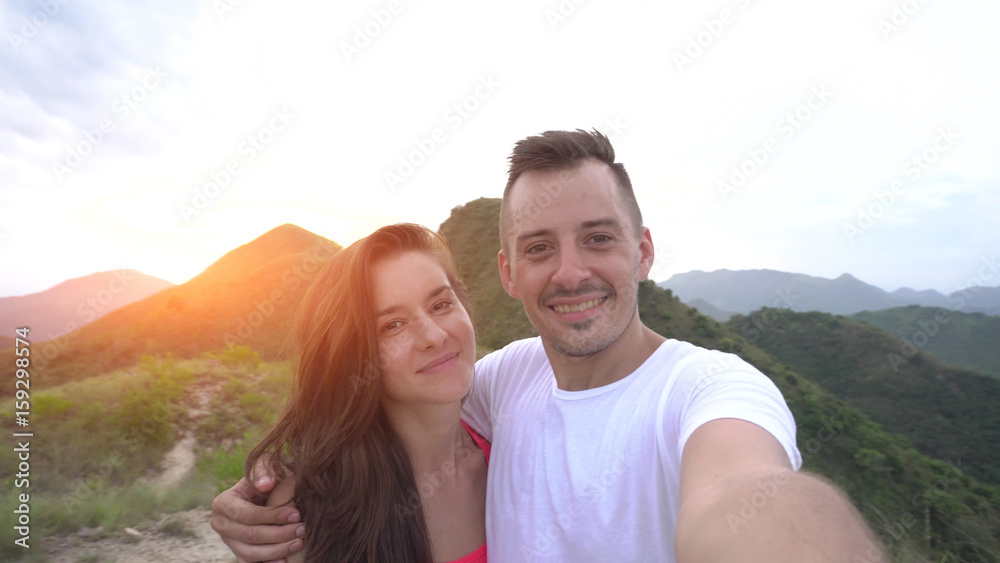 Young couple taking selfie, laughing in the mountains