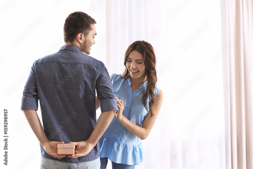 Handsome man hiding gift for girlfriend behind back Handsome man hiding gift for girlfriend behind back