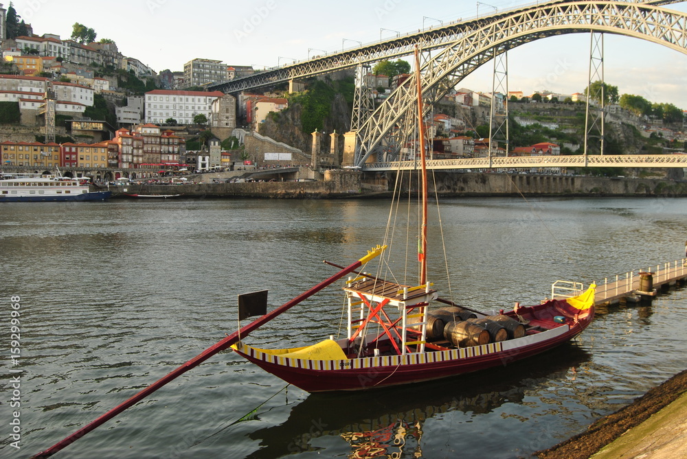 Barco rabelo amarelo e vermelho parado no rio d'ouro no porto portugal com ponte Dom Luís de fundo