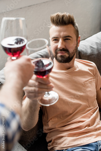 homosexual couple clinking with wine while spending time at home