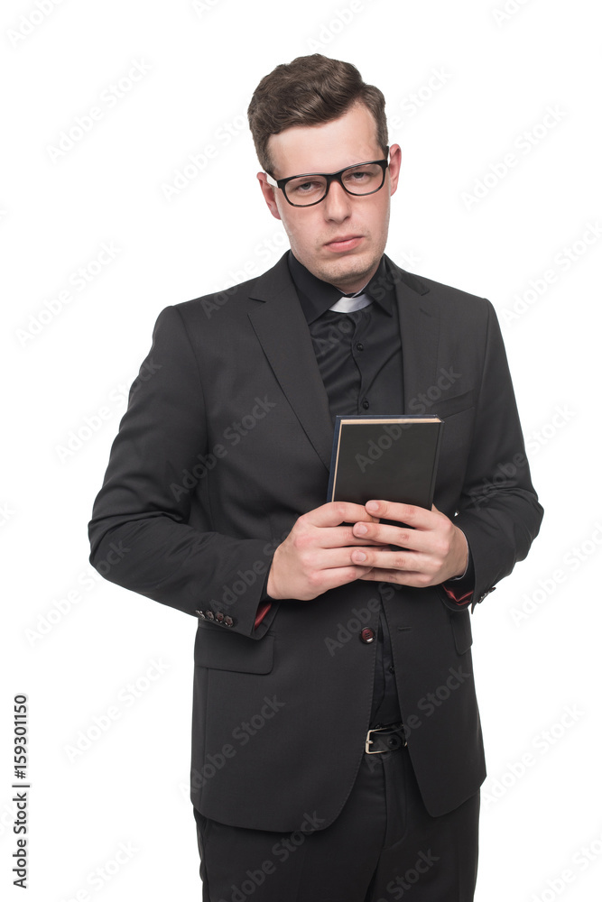 young priest in black suit holding scripture book and looking at camera isolated on white young priest in black suit holding scripture book and looking at camera isolated on white