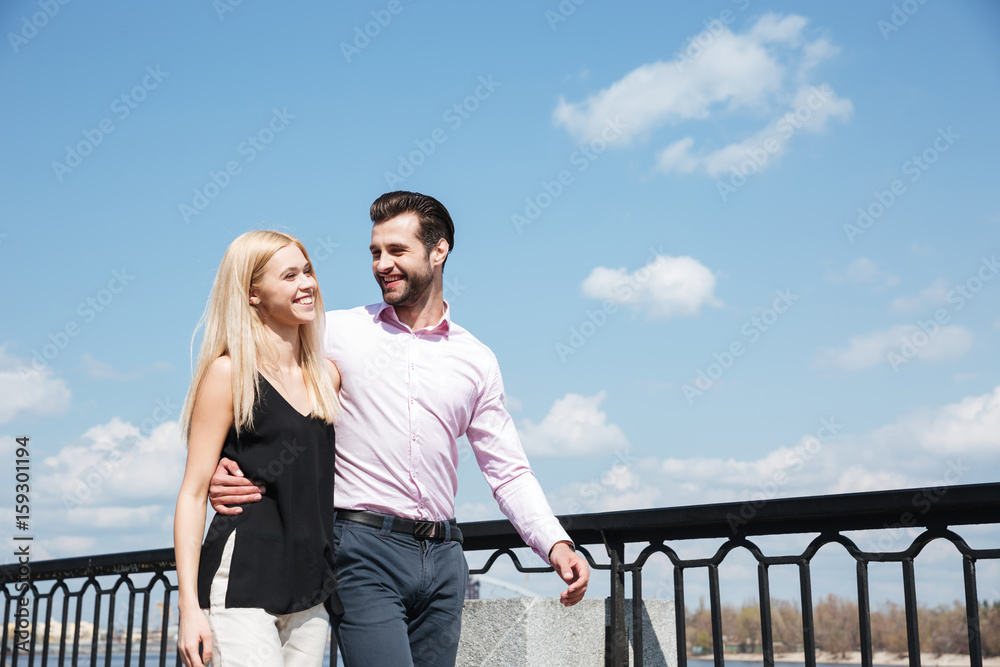 Pretty couple of cheerful man and woman walking in street