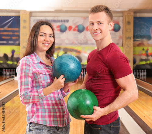 Happy couple playing bowlin...