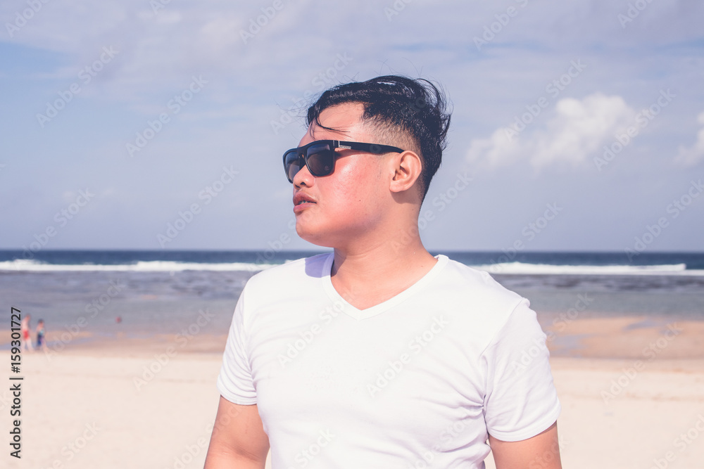 Young asian indonesian man on the beach of tropical Bali island, Indonesia.