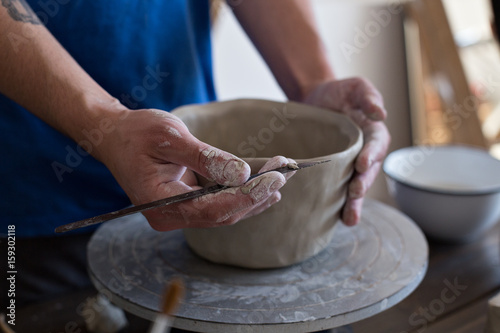Close up of male hands and nails dirty with clay and other artistic materials needed to create pot or sculpture, molding and craving out details