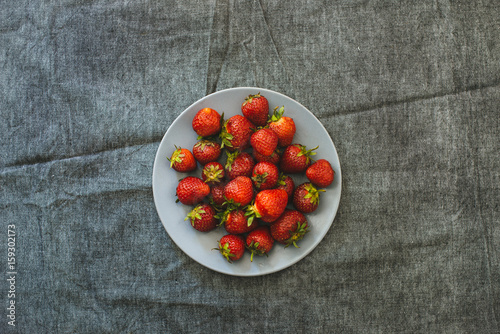 Bowl of fresh strawberry on a background of gray linen
