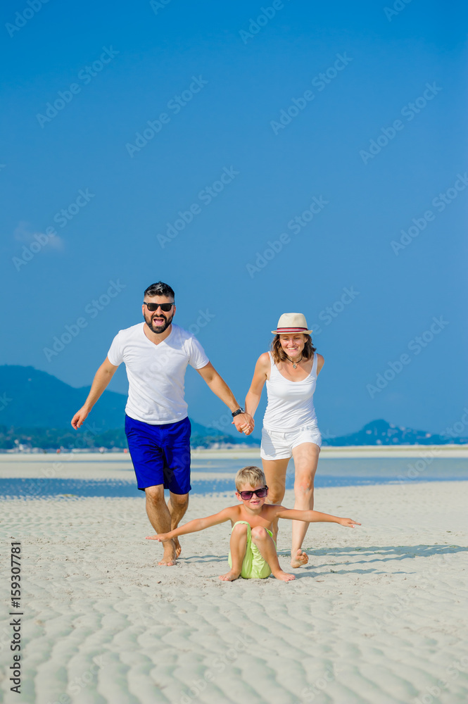 Happy young family of three having fun on the desert sunny beach Happy young family of three having fun on the desert sunny beach