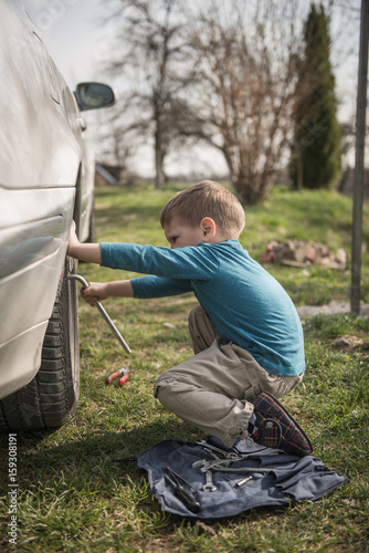 Little boy fixing car tyre