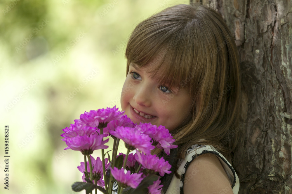 Little cute smiling girl in a hat holding a bouquet of flowers Little cute smiling girl in a hat holding a bouquet of flowers