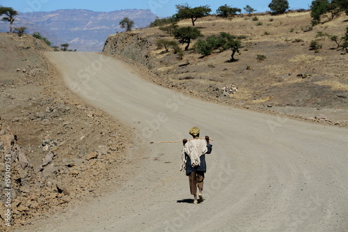 A solitary man walks down a long lonely road