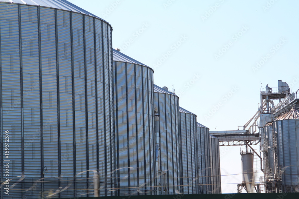 Large metal containers for grain storage. Elevator. Large metal barrels.