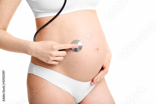 Pregnant woman holding stethoscope on belly