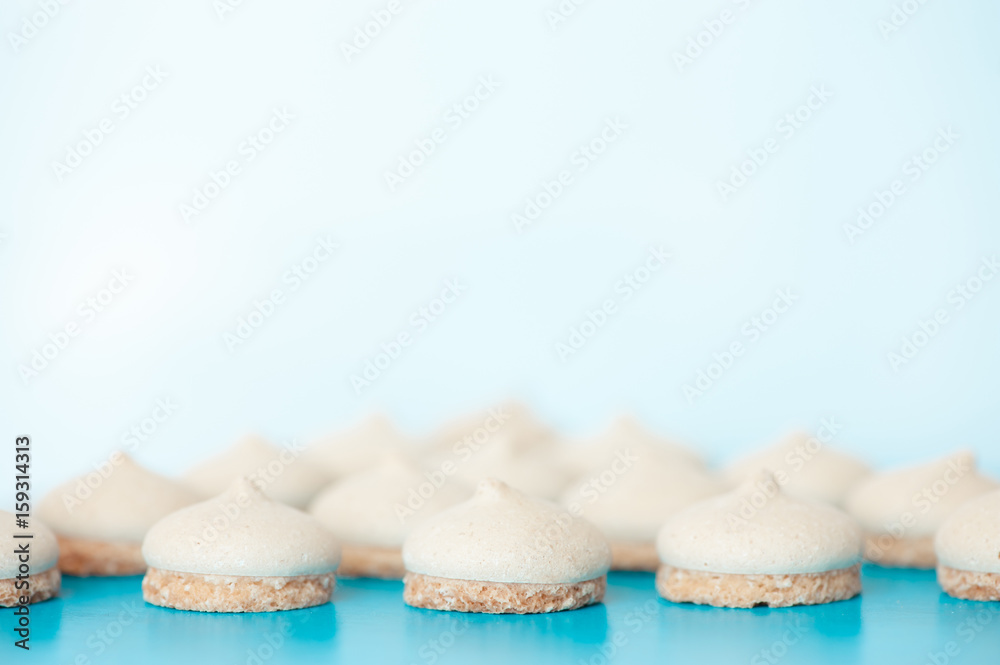 Small white cakes on a blue background. In the distance they are blurred. Small white cakes on a blue background. In the distance they are blurred.