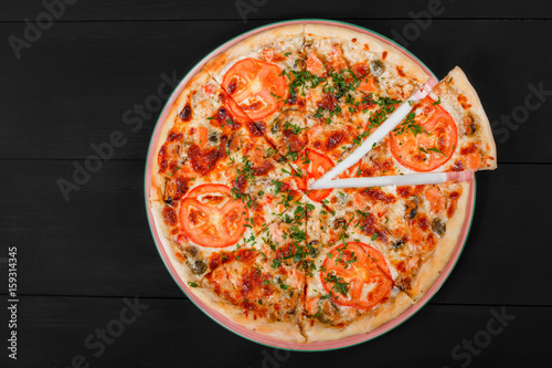 Pizza with chicken, tomatoes, mushrooms, greens and cheese on dark wooden background. Homemade pizza. Top view