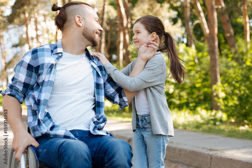 Delighted man touching ear of his daughter