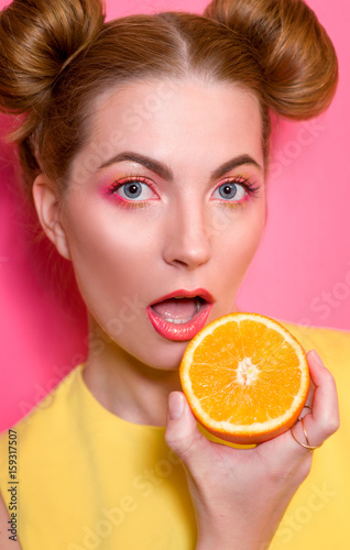 portrait of cute attractive blonde young woman with colorful makeup with oranges in her fingers